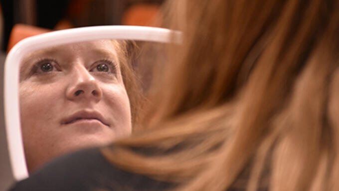 Participant in a makeup session at a teacher's convention looks into a mirror