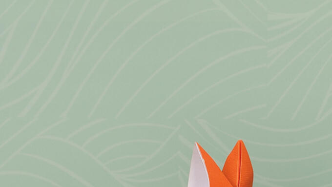 an orange oragami fox sitting on 5 children's books