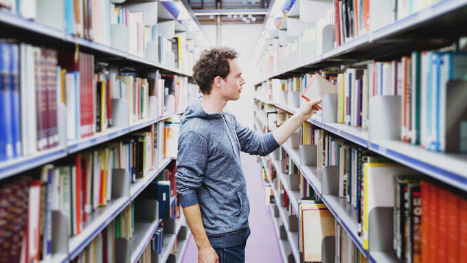 Man standing between the shelves of a library