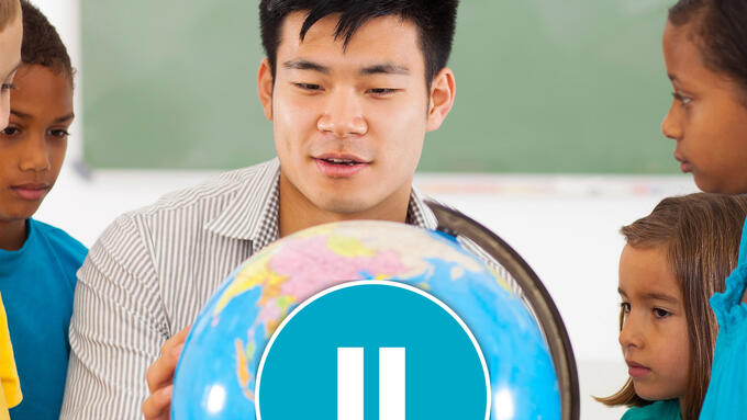 Young male teacher shows off globe to students
