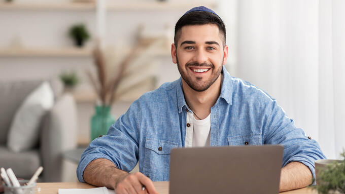 Young man sits infront of laptop