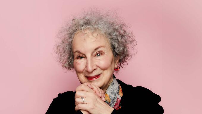 Women with curly grey hair clasping her hands at chin