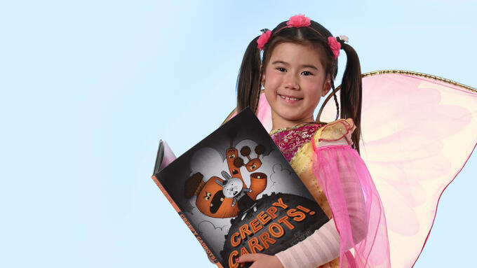 A young person holding a copy of a book titled Creepy Carrots 
