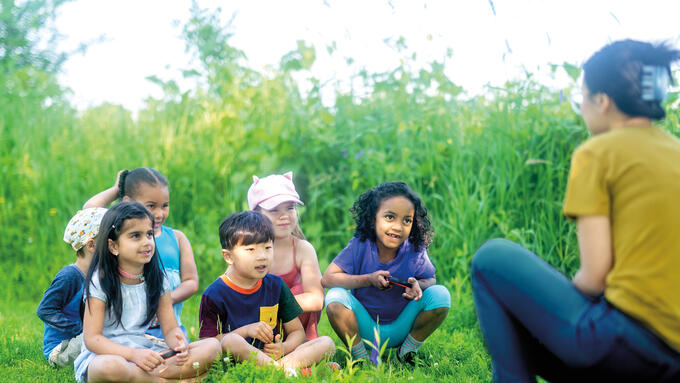 A teacher speaks to students in an outdoor setting
