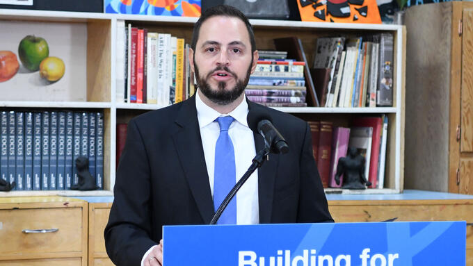 Man wearing blue tie speaks and a podium with sign reading Building for the Future