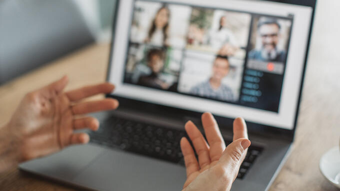 Someone explaining with their hands to a group online chat