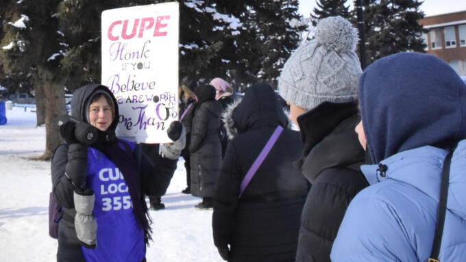 Striking workers hold signs