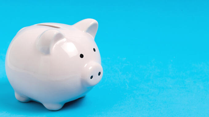 a light blue background with a white piggy bank in the foreground