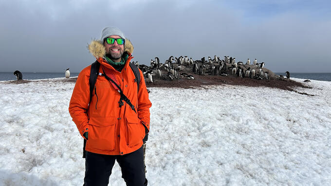 A man stands in front of a group of penguins