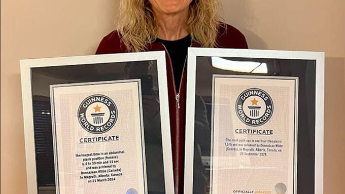 A woman holding two framed Guiness world records