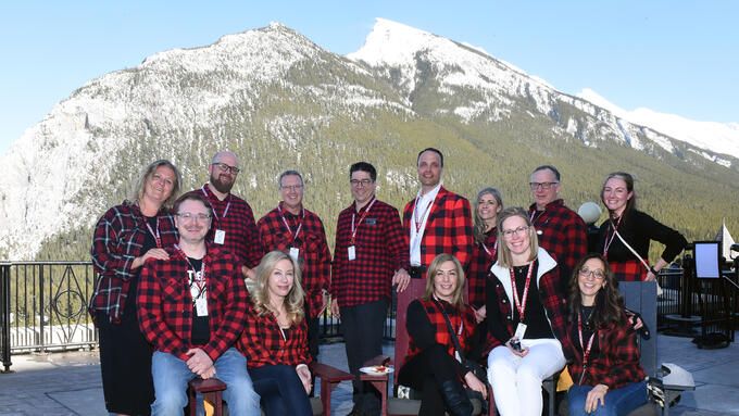 Group of people wearing lumberjack shirts infront of mountian