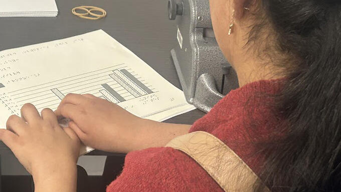 Student at desk reading braille 