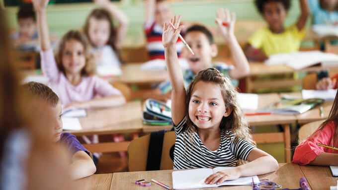 A couple of elementary students raising their hands eagerly to speak french