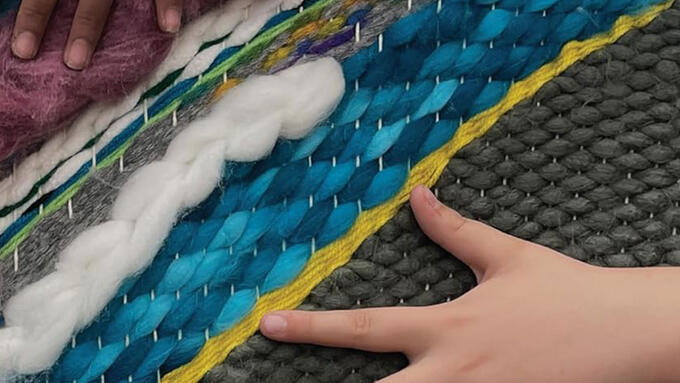 Kids hands feeling a woven fabric with many colours and textures