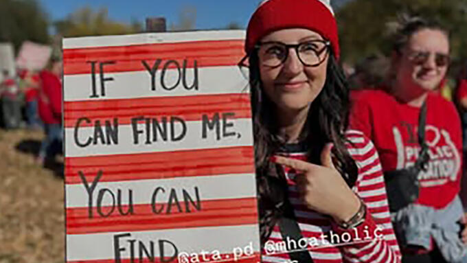 A person wearing a Where's Waldo costume holding a sign