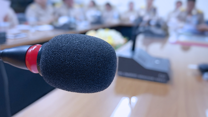 Close up of a meeting microphone in front of a table top meeting