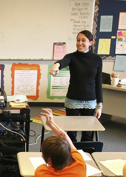 A teacher points to one of her students in a classroom