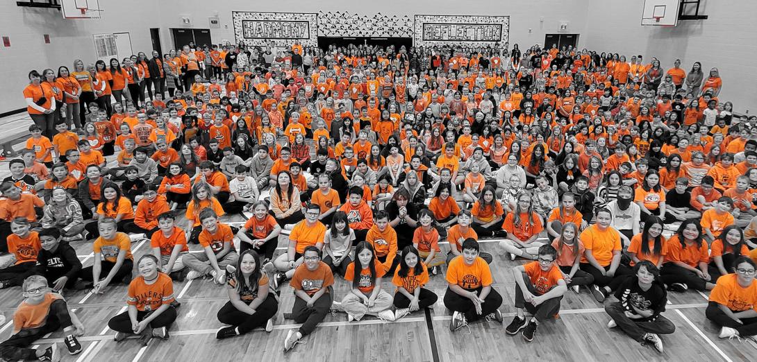 School assembly with children wearing orange t-shirts 
