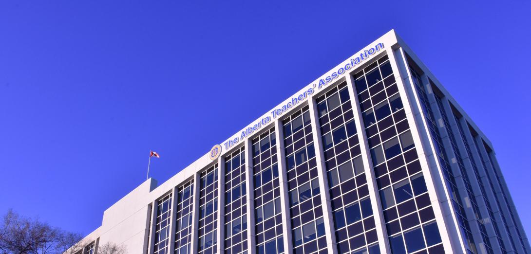A blue sky background free of clouds. In the foreground is a white building with columns of blue windows. The canadian flag flies from the top of the building. The ATA logo and the text "Alberta Teachers' Association" are also on the front facade.