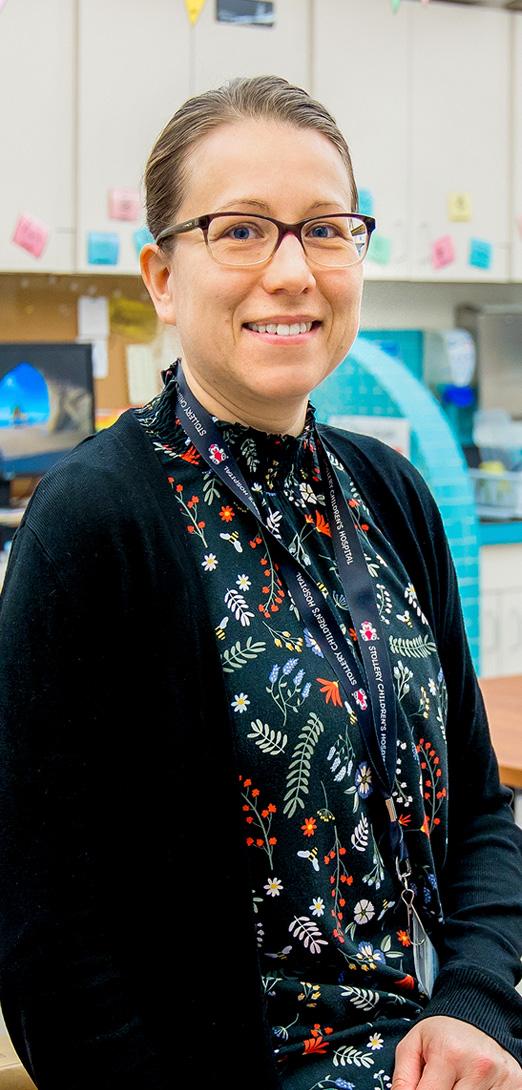A teacher in a black cardigan and glasses smiling for the camera