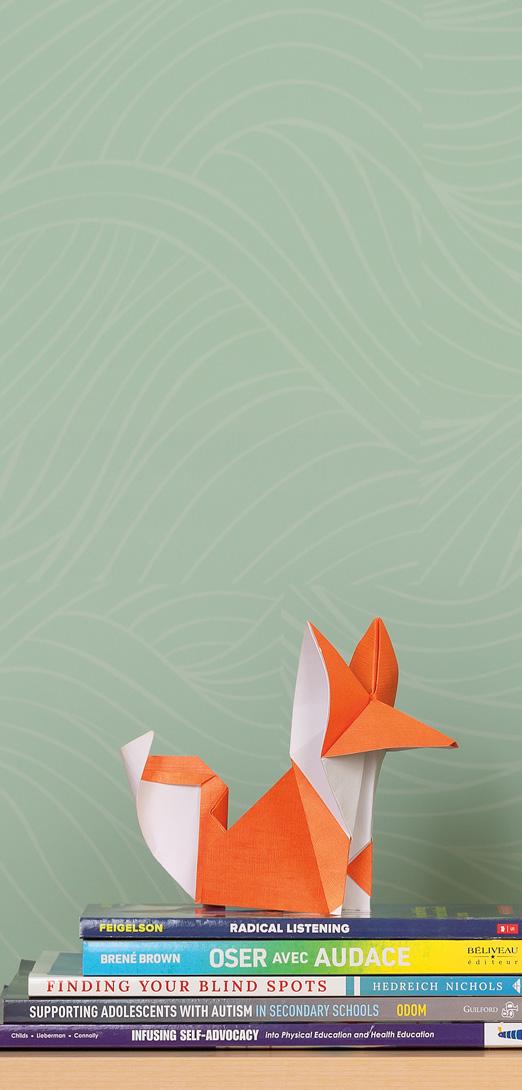 an orange oragami fox sitting on 5 children's books