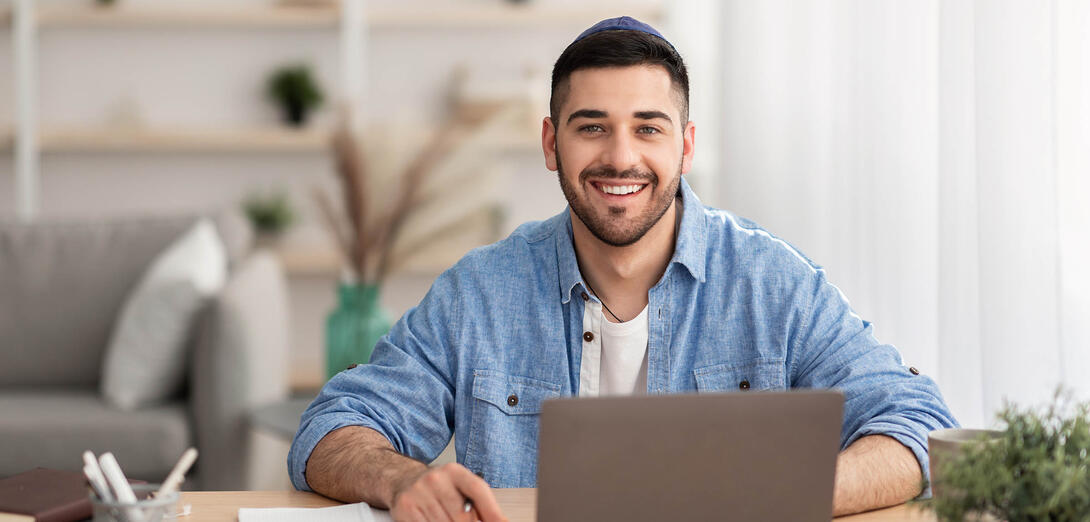 Young man sits infront of laptop