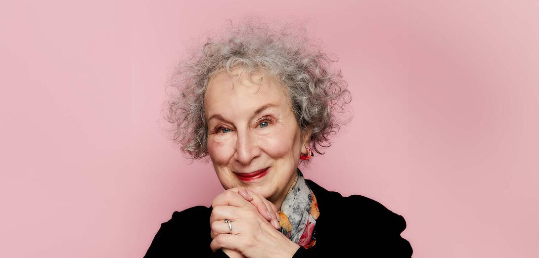 Women with curly grey hair clasping her hands at chin