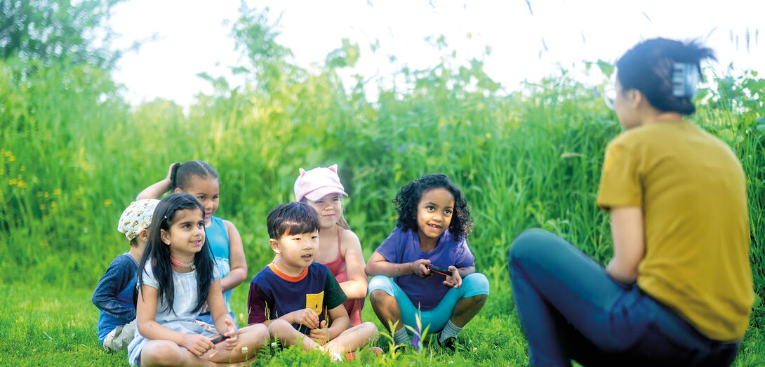 A teacher speaks to students in an outdoor setting