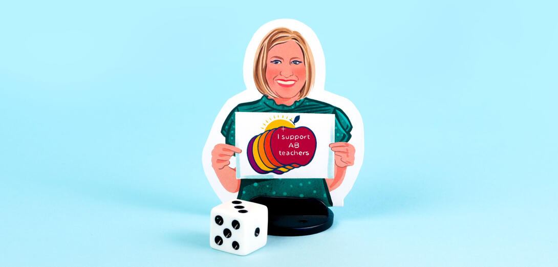 An illustrated boardgame player piece sits on a blue background in front of a die. The illustration of Melanie shows her with a blonde bob hairstyle, wearing a green short-sleeved shirt, holding a "I support AB teachers" graphic.