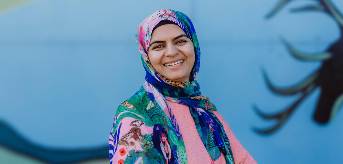 Profile photo of Huma Kashif in front of a local mural in Slave Lake.