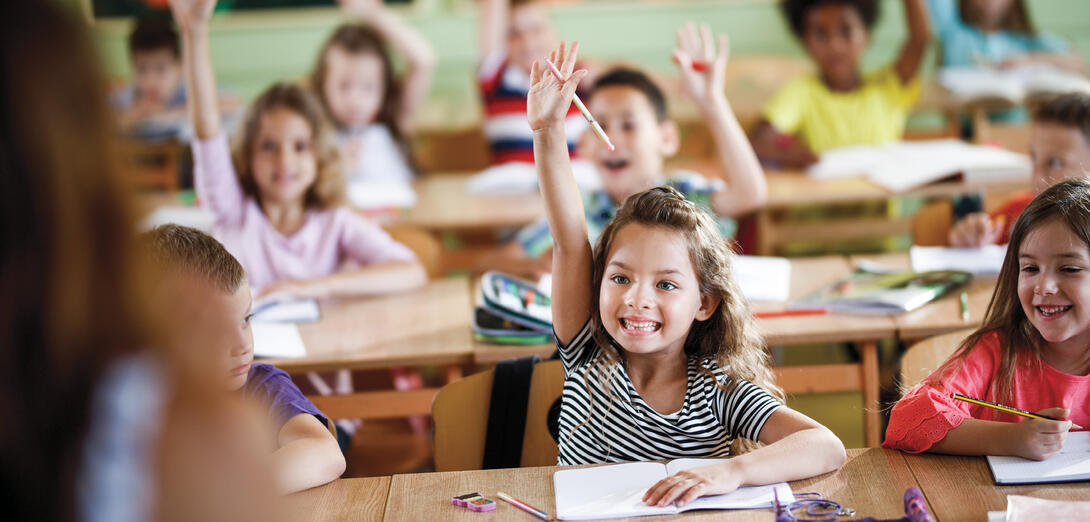 A couple of elementary students raising their hands eagerly to speak french