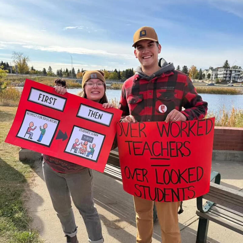 Two people holding signs at a rally